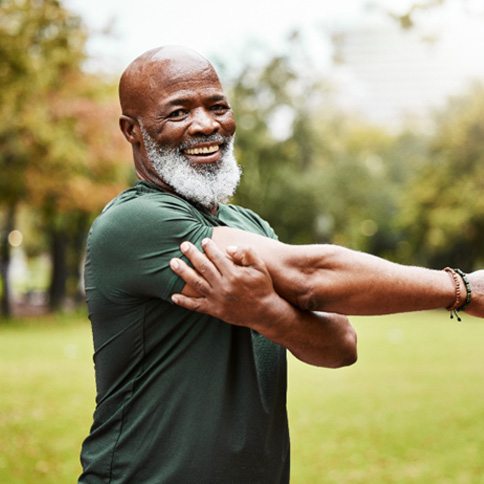 Senior man standing in field and stretching