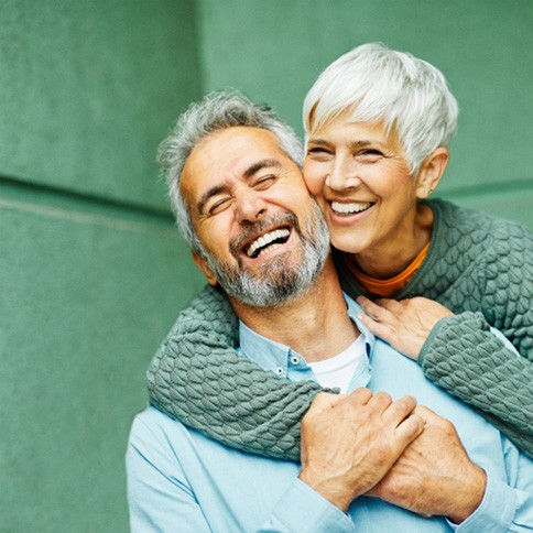 Senior woman hugging senior man from behind