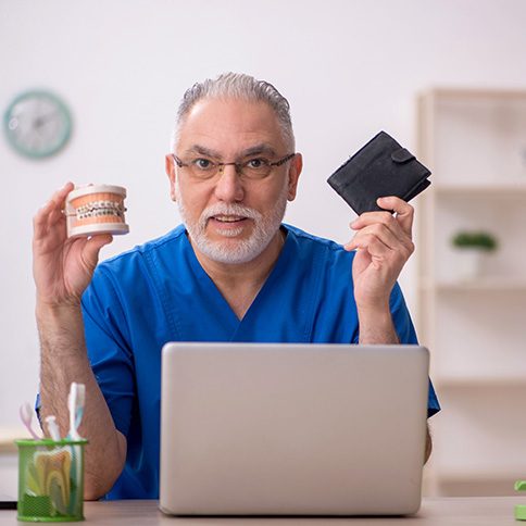 A dentist holding up a jaw mockup with braces and a wallet