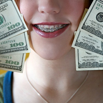 A smiling girl with braces holding hundred-dollar bills next to her face