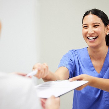 A dentist handing a dental insurance form to a patient