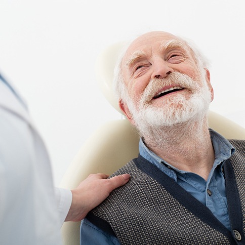 Senior man in dental chair looking up at dentist