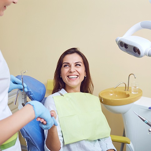 Smiling patient shaking hands with her dentist