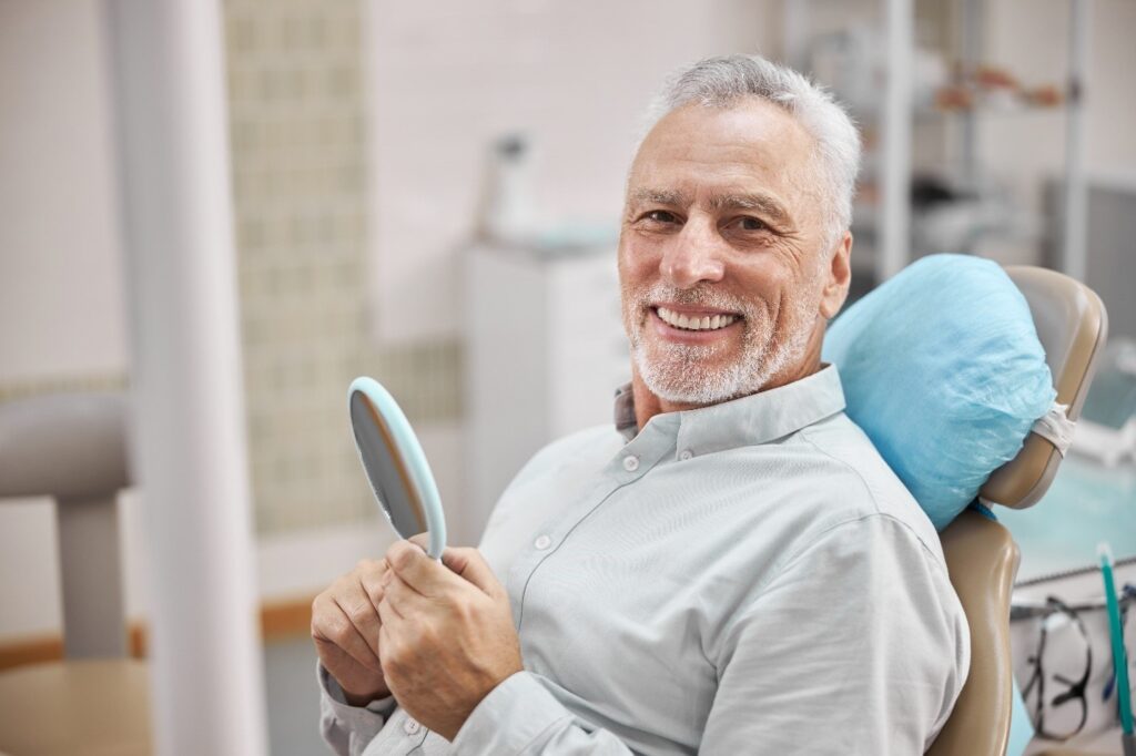 person with straight teeth smiling at reflection